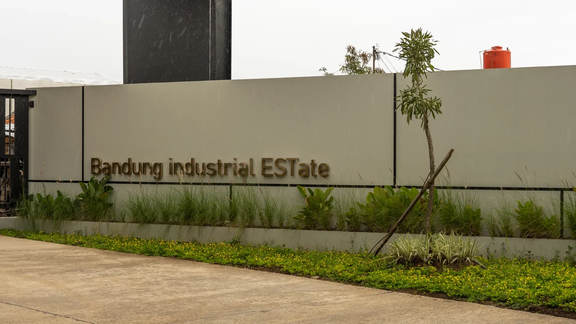 Papan nama Bandung Industrial Estate dengan taman hijau di area gerbang